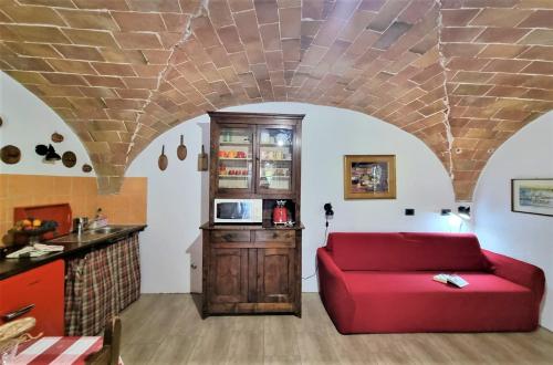 a living room with a red couch and a kitchen at Urlaub, wo die Toskana noch authentisch ist - Rustico aus 16Jh mit Infinity Pool in Pomarance