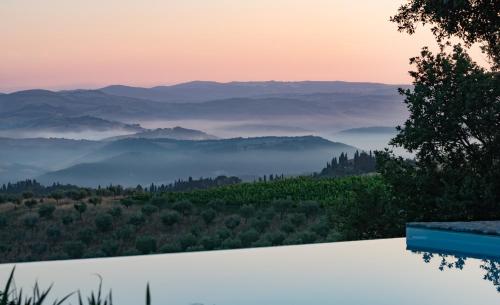 a view of the mountains from a swimming pool at sunset at Urlaub, wo die Toskana noch authentisch ist - Rustico aus 16Jh mit Infinity Pool in Pomarance
