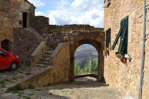 an archway in an old stone building with a red car at Urlaub, wo die Toskana noch authentisch ist - Rustico aus 16Jh mit Infinity Pool in Pomarance