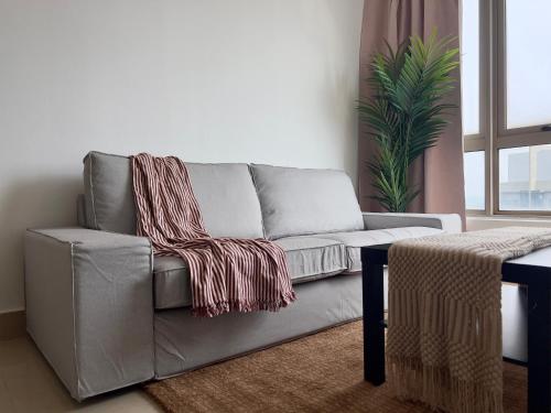 a gray couch in a living room with a plant at Shaftsbury Cyberjaya in Cyberjaya