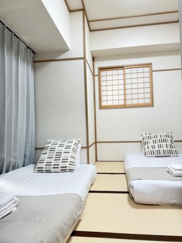 two beds in a room with a window at Apartment Hotel Side of Shinsaibashi Shopping street in Osaka