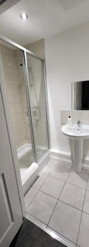 a white bathroom with a shower and a sink at 4 Bedroom Home Tameside Greater Manchester Sleeps 8 in Manchester