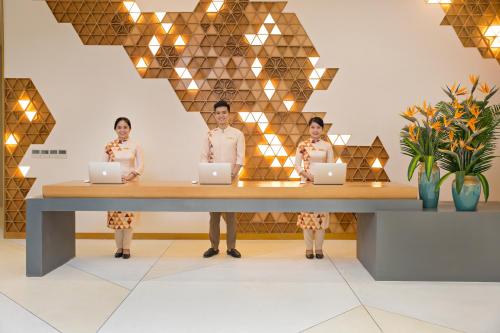 three women standing at a table with laptops at TMS Hotel Da Nang Beach in Da Nang