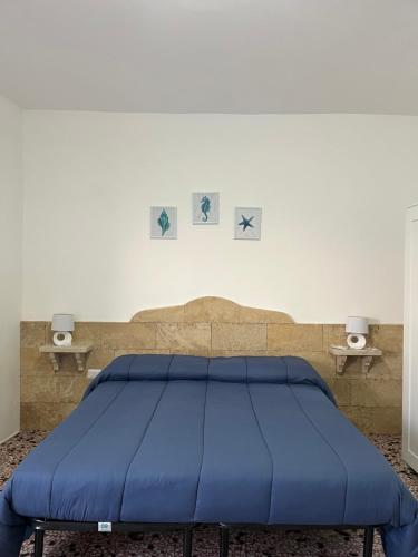 ein blaues Bett in einem Raum mit zwei Tischen in der Unterkunft MONOLOCALE LA GROTTA in Capilungo