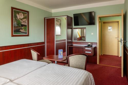 a hotel room with a bed and a table and a desk at OREA Resort Panorama Moravský kras in Blansko