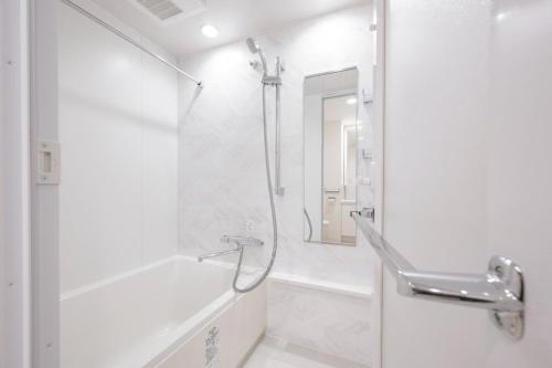 a white bathroom with a shower and a sink at Grand Concierge Roppongi in Tokyo