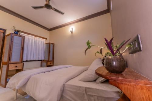 a bedroom with a bed with a plant on a table at Aavya Wellness Retreat Center in Rishīkesh
