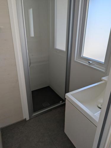 une salle de bain avec une douche avec un lavabo et un miroir dans l'établissement Mobil Home climatisé à 3 minutes de la Mer, au Grau-dʼAgde