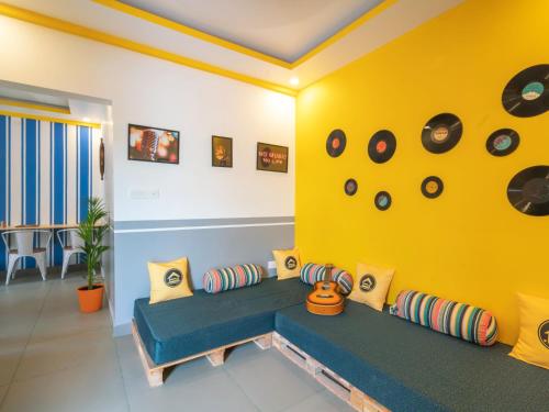 a living room with a blue couch and a yellow wall at The Hosteller Fort Kochi in Cochin