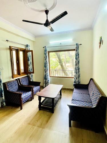 a living room with couches and a table and a window at Himalaya view cottage, machkhali , Ranikhet in Shitlakhet