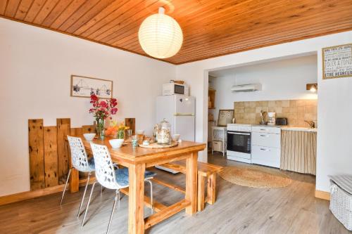 une cuisine et une salle à manger avec une table et des chaises en bois dans l'établissement 60 m de la plage - Jardin - Terrasse - Maison pour 5, à La Guérinière