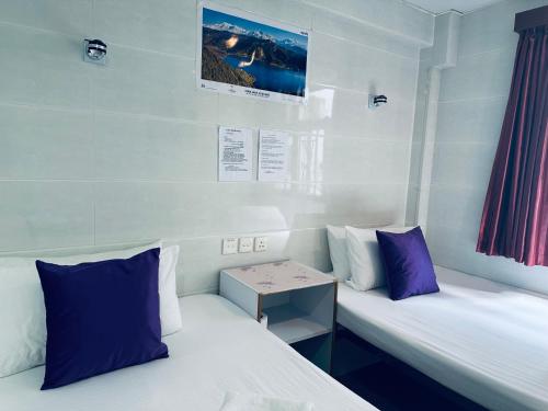 two beds in a room with purple and white pillows at KATHMANDU GUEST HOUSE in Hong Kong
