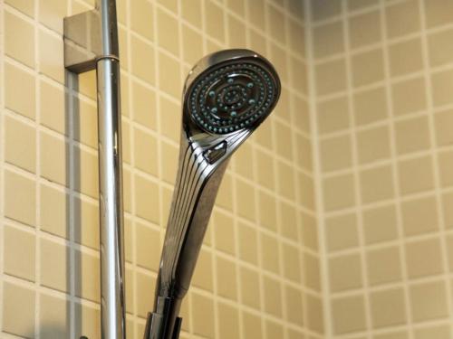 a shower head in a bathroom with yellow tiles at Rembrandt Cabin Shinjuku Shin-Okubo in Tokyo