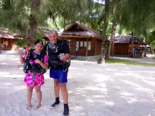 a man and a little girl standing in the sand at Fadhila cottage and dive resort in Pulau Togian