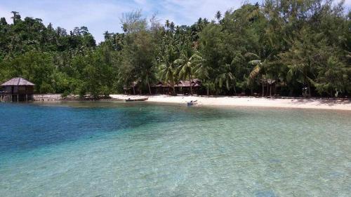 a beach with a boat in the water at Fadhila cottage and dive resort in Pulau Togian