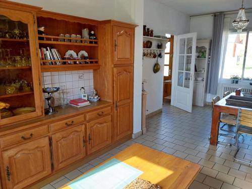 a kitchen with wooden cabinets and a table at Maison de charme dans la Somme in Miraumont