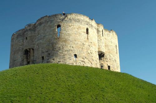 a castle on top of a grassy hill at Fossgate Bridge Apartments York in York