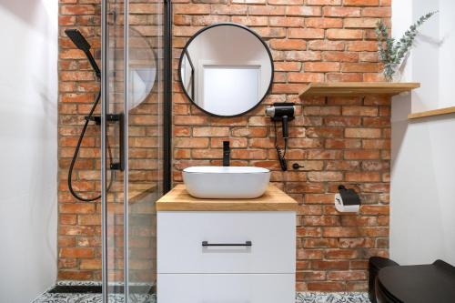 a bathroom with a sink and a mirror on a brick wall at Podmurna Zakątek in Toruń