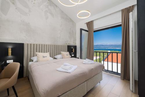 a bedroom with a large bed and a large window at Villa SUNSET II with private pool and beautiful sea view in Vrbnik