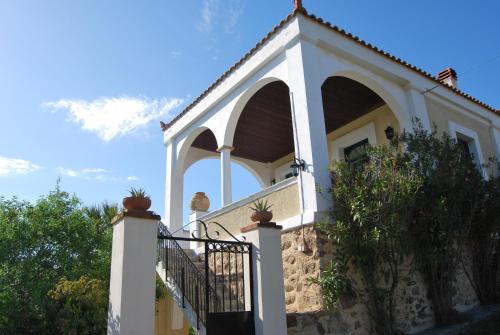 a white building with an arch and a fence at Spiti Limnos, Idyllisch Gelegen Im Orangenhain in Límnos