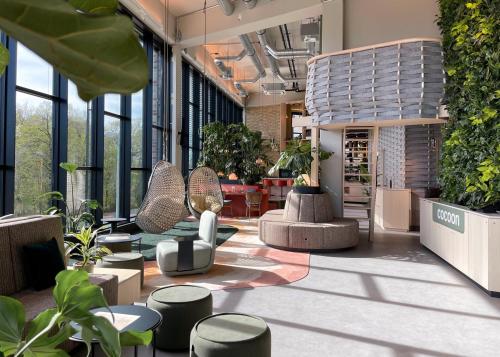 a lobby with chairs and plants in a building at Cocoon Theresienwiese in Munich