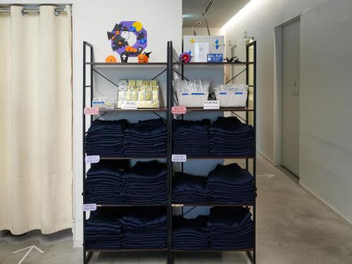a shelf filled with blue shirts in a room at Rembrandt Cabin Shinjuku Shin-Okubo in Tokyo