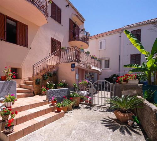 a building with a bunch of potted plants and stairs at Apartments Fortuna in Novalja