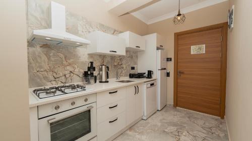 a kitchen with white cabinets and a stove top oven at Mucize Residence in Fethiye