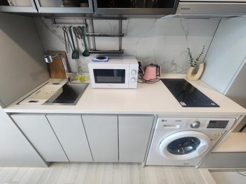a small kitchen with a microwave and a washing machine at Brand New Residence with Family in Busan