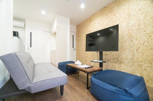 a living room with a blue chair and a tv at Laina Kyobashi2 in Osaka