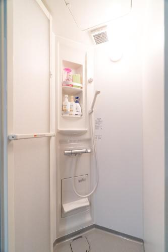 a white refrigerator in a bathroom next to a shower at Laina Kyobashi2 in Osaka