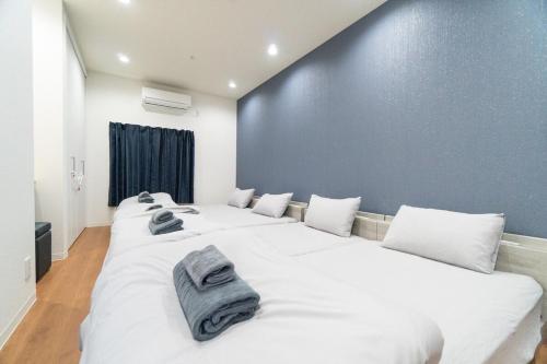 a bedroom with three beds with towels on them at Laina Kyobashi2 in Osaka