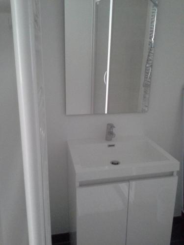 une salle de bain blanche avec un lavabo et un miroir dans l'établissement Agréable studio à proximité du centre ville, à Tarbes