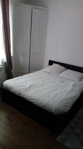 une chambre avec un lit avec des draps blancs et une fenêtre dans l'établissement Agréable studio à proximité du centre ville, à Tarbes