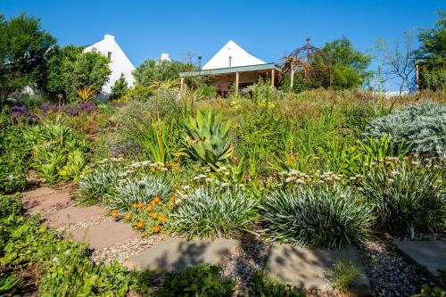 a garden with flowers and plants in front of a house at The Blomhuis Apartments in McGregor