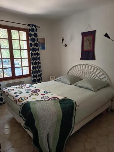 une chambre avec un grand lit avec une couverture dessus dans l'établissement fleur de gaïa chambres d'hôtes, à Mazan
