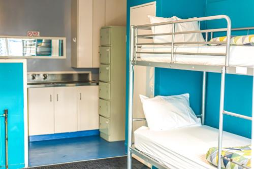 a room with two bunk beds and a kitchen at Crashpalace Backpackers in Rotorua