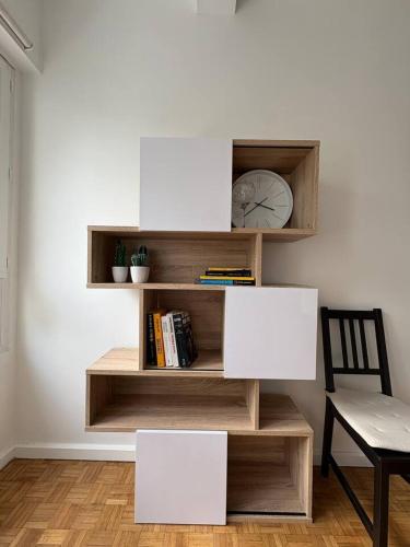 une étagère avec une horloge et une chaise dans une pièce dans l'établissement L'appart du Parc Malo, à Dunkerque