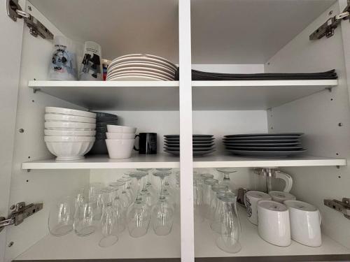 a shelf with glasses and plates and dishes on it at L'appart du Parc Malo in Dunkerque