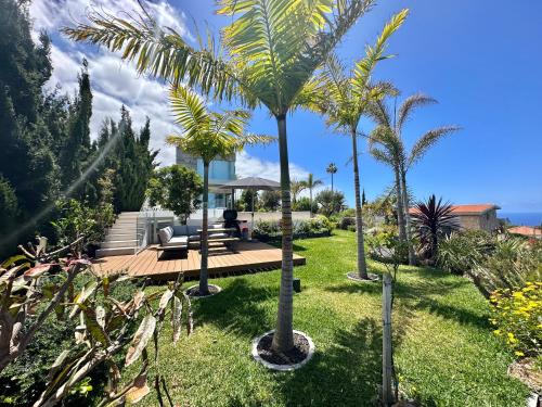 a garden with palm trees and a wooden deck at Villa Deluxe - Jardin del Mar y Cielo in Tacoronte
