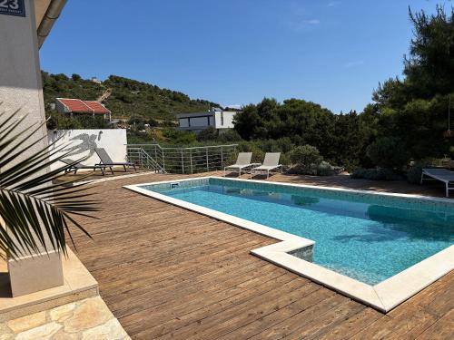 a swimming pool on a wooden deck next to a house at Villa Lastavica in Vis