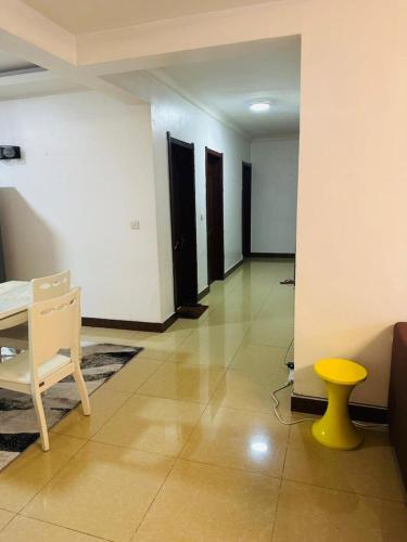 a room with a table and chairs and a yellow stool at R&R Swahili Modern Appartments in Dar es Salaam