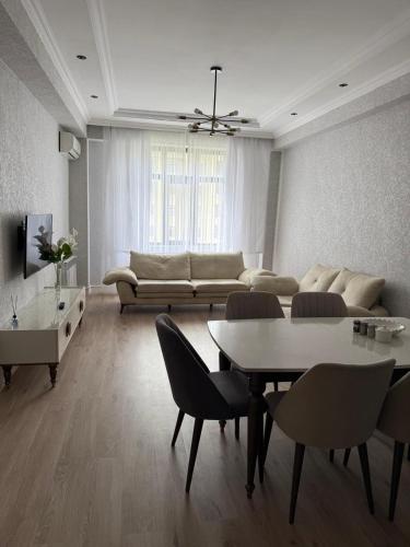 a living room with a couch and a table and chairs at Mart's 3 room apartment in Sumqayyt