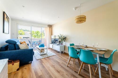 un salon avec un canapé bleu, une table et des chaises dans l'établissement Cassis - Le Capucine, 4pers, terrasse, classé 3 étoiles, à Cassis