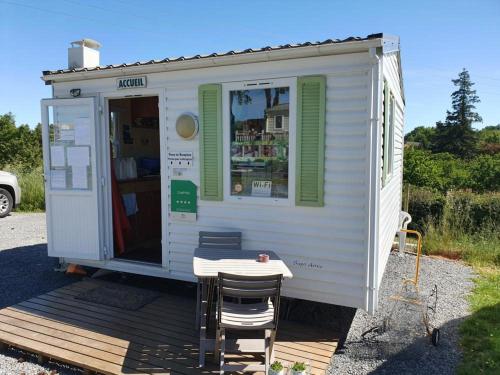un hangar blanc avec une table et des chaises dans l'établissement CAMPING VILLAGE PUYROND Bressuire, à La Celle-sous-Gouzon