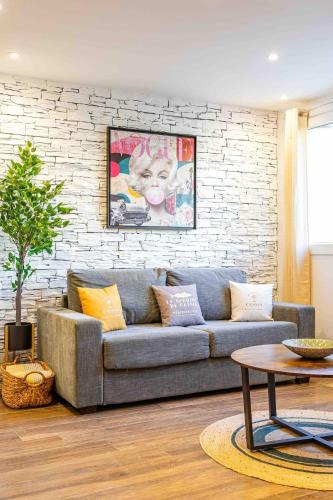 un salon avec un canapé et un mur de briques dans l'établissement Cassis le Marignan- rdc - garage - classé 3 étoiles, à Cassis