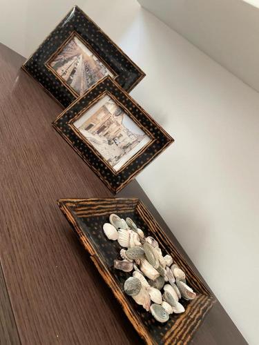 three pictures and some rocks in a wooden tray at Casa di nonna Pina in Manduria