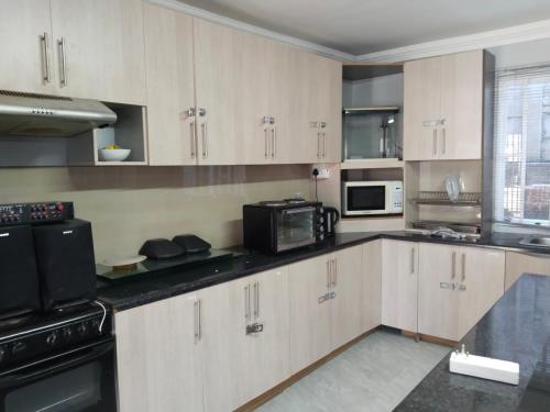 Una cocina con gabinetes blancos y electrodomésticos negros. en Silverstreams Guest house, en Mthatha