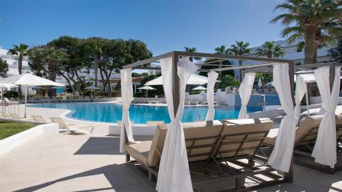 a group of chairs and umbrellas next to a pool at BLUESEA Club Martha's in Cala d´Or