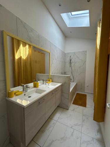 une salle de bain avec un lavabo, un miroir et une baignoire dans l'établissement Les maisons de Lina, à Les Mées